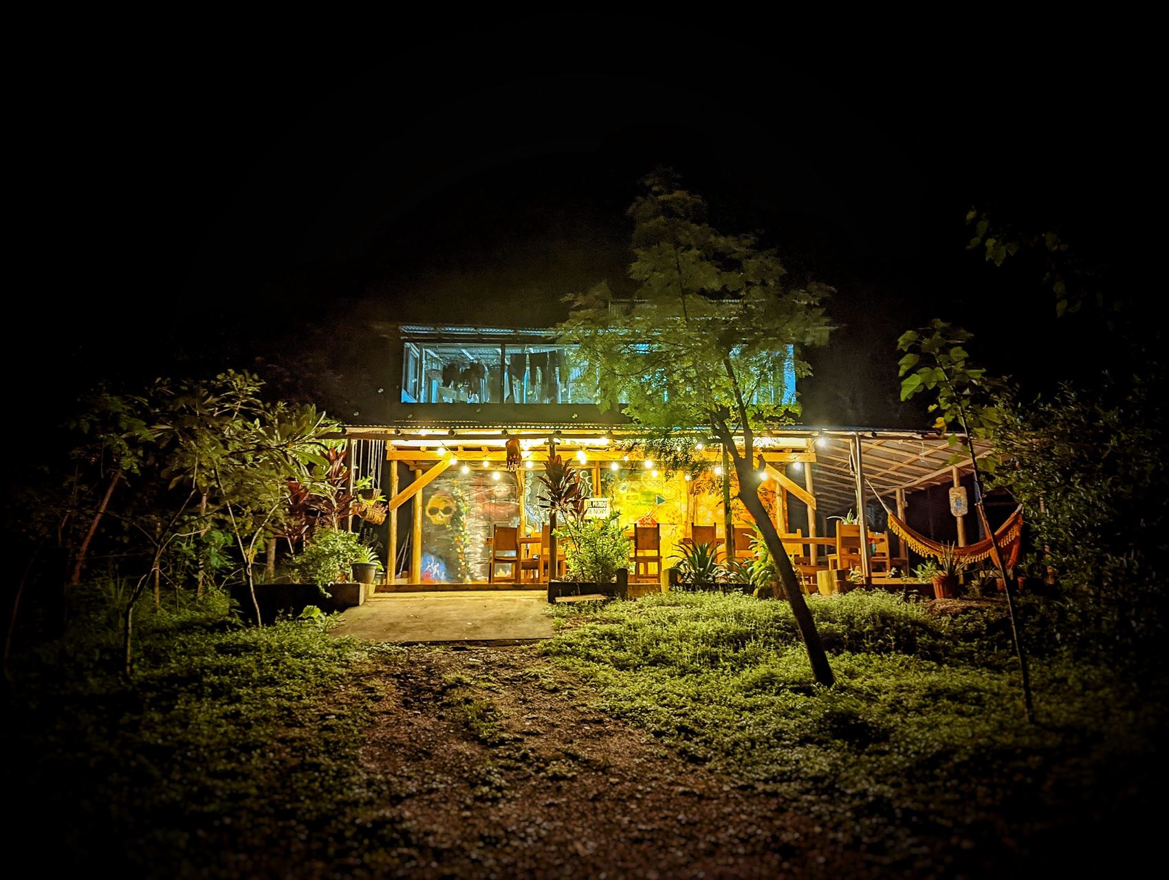 The house at night, lit from within, seen from the garden.